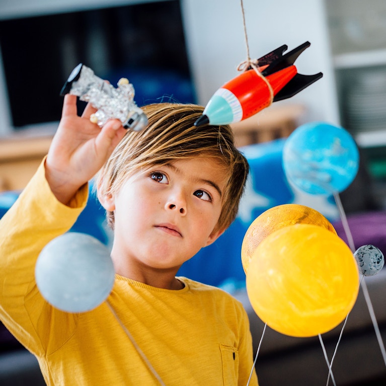 A young child playing with his toy astronaut