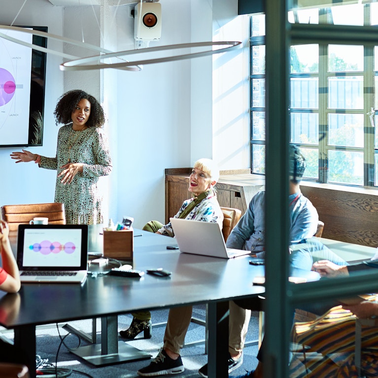 Mid adult woman delivering meeting in board room