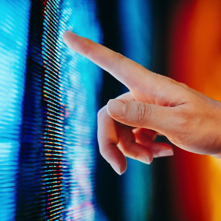 Close up of woman's hand touching illuminated and multi-coloured LED display screen