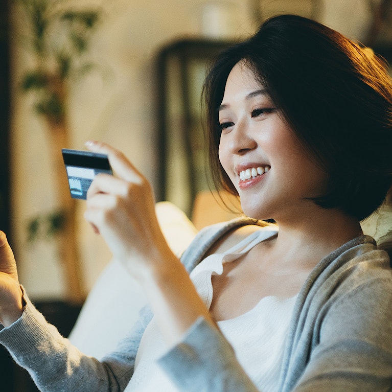 Young Asian woman shopping online on her smartphone and making mobile payment with credit card