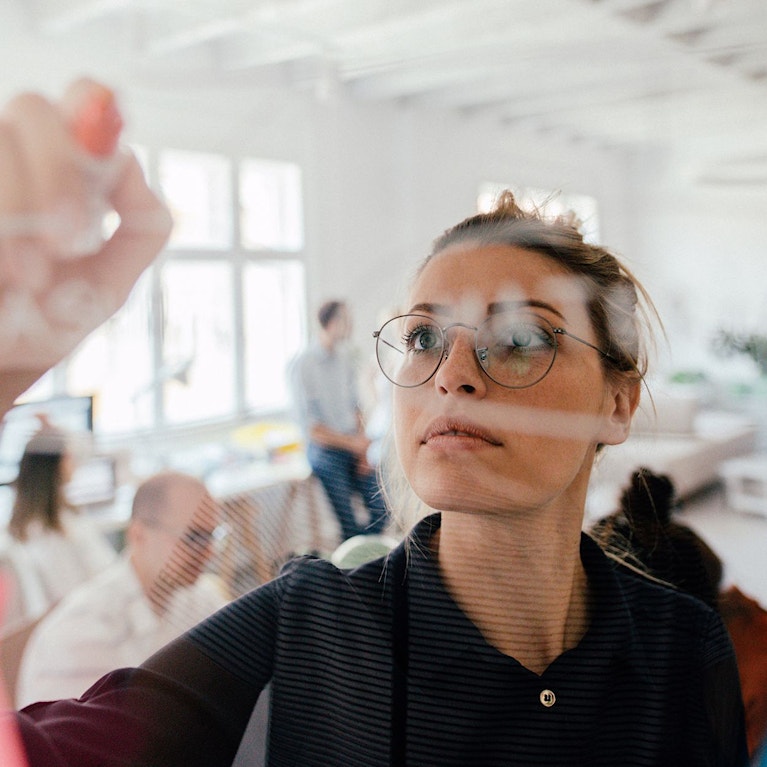 Woman making plans on transparent wipe board