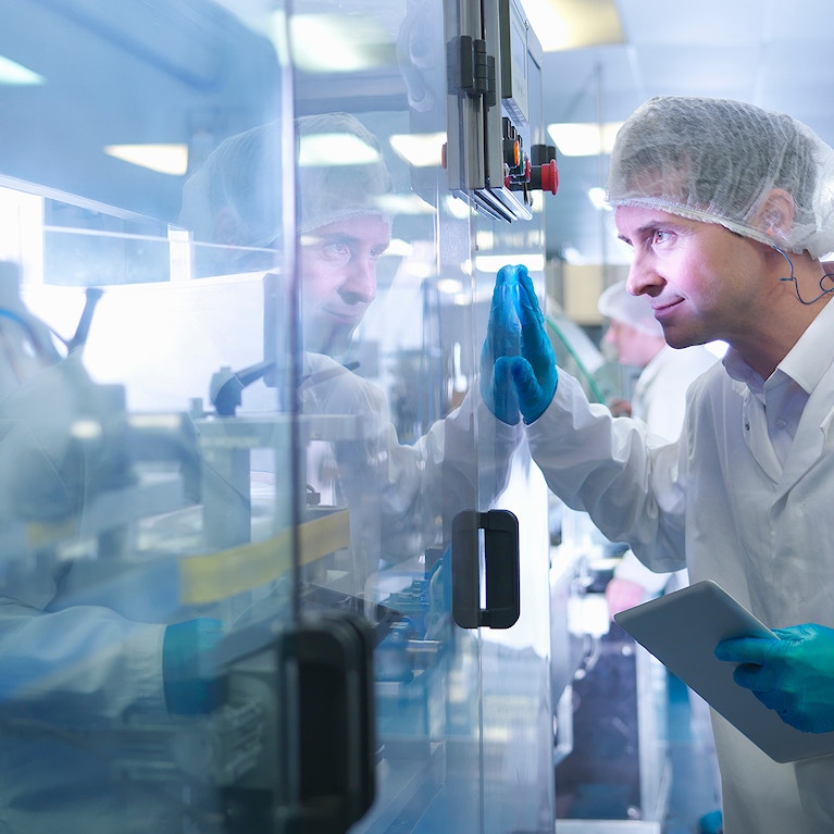 Worker inspecting tablets as they are put into packaging in pharmaceutical factory