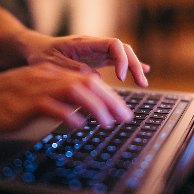 Hands typing on laptop