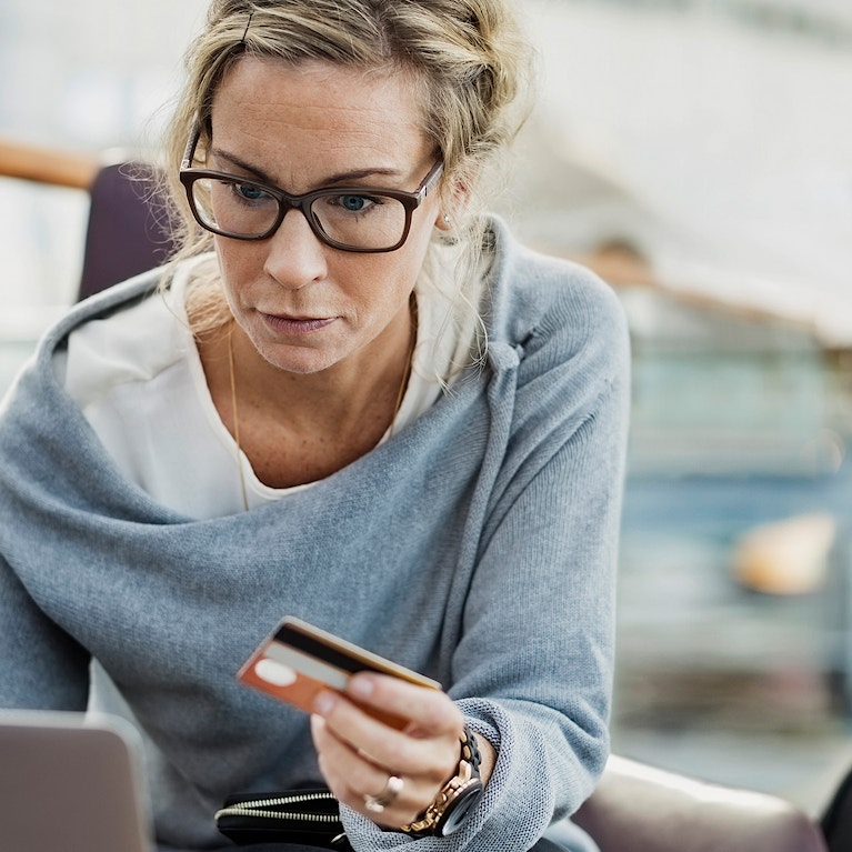 Woman holding credit card with laptop and suitcase