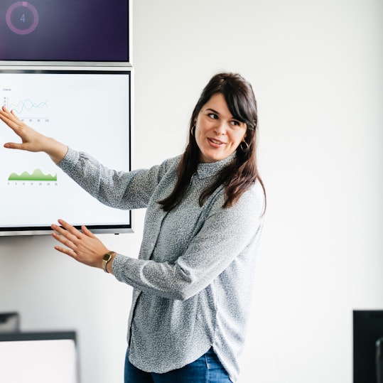 Woman presenting data on a large screen.