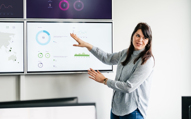 Woman presenting data on a large screen.