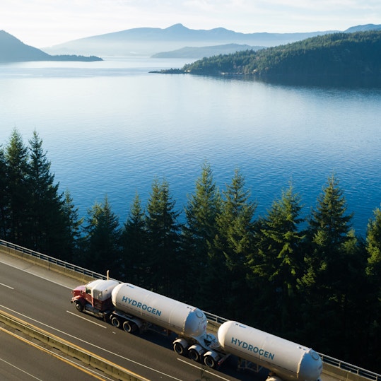 Hydrogen tanker truck driving on lakeside highway