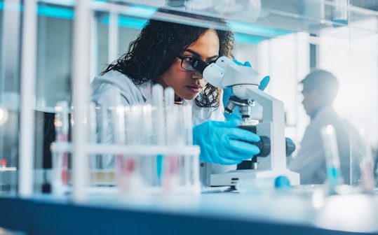 Life sciences researcher looking through microscope