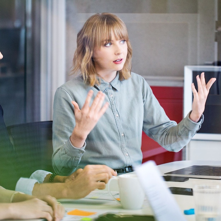 Person speaking to others in an office meeting room