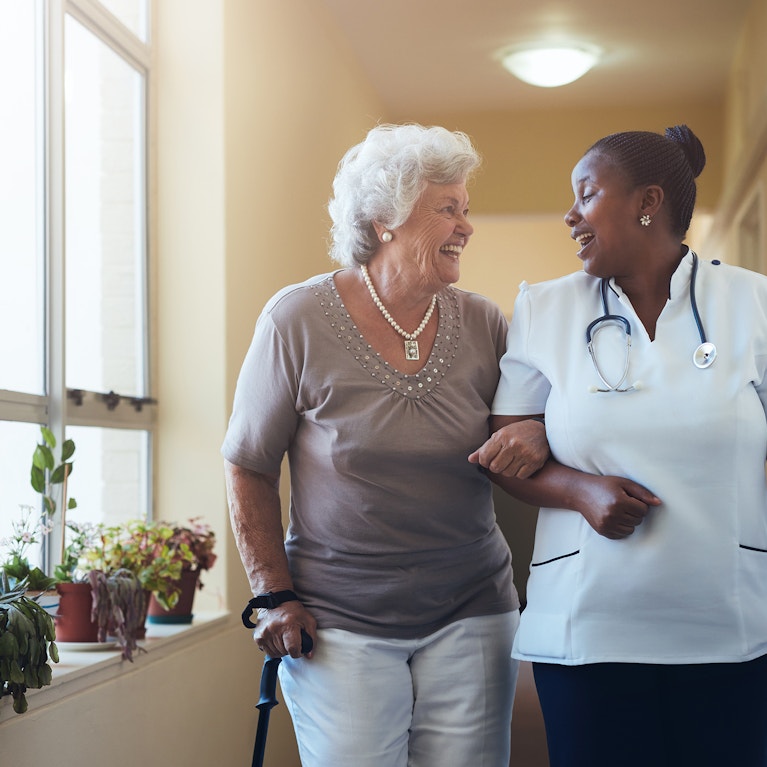 Smiling healthcare worker and senior woman walking together