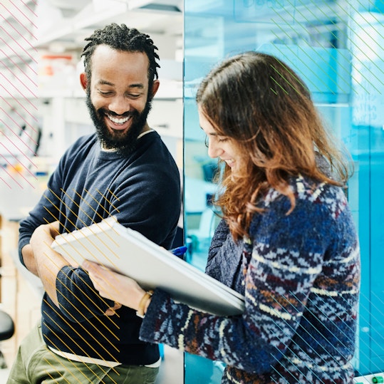 Two people in an office smiling and talking to each other