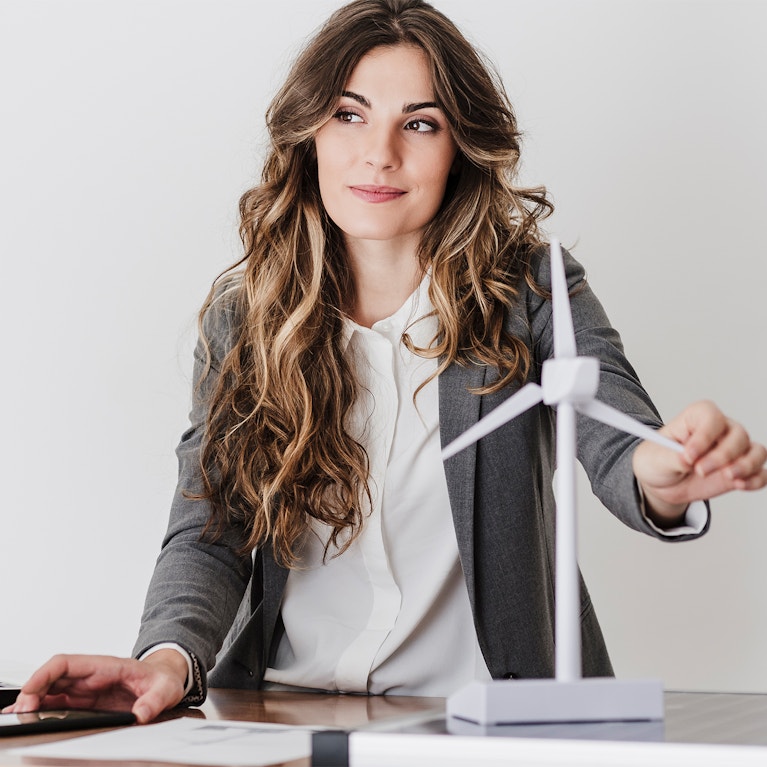 Female engineer working in modern office holding wind turbine model