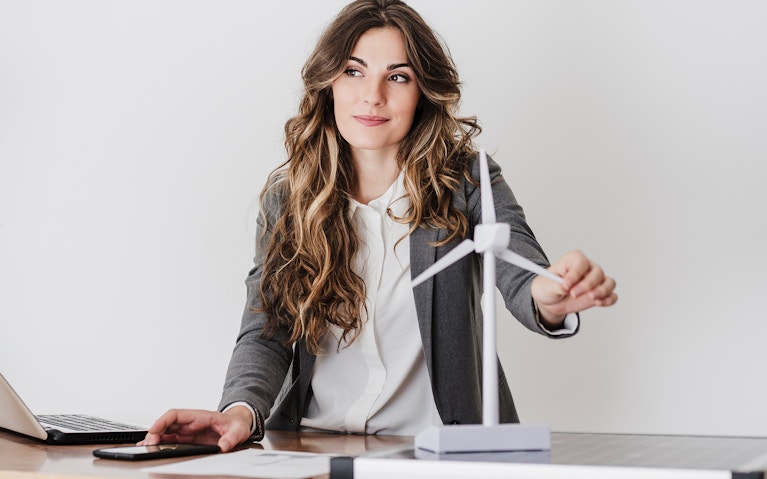 Female engineer working in modern office holding wind turbine model