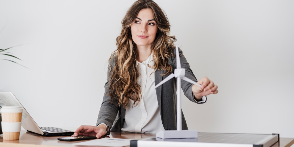 Female engineer working in modern office holding wind turbine model