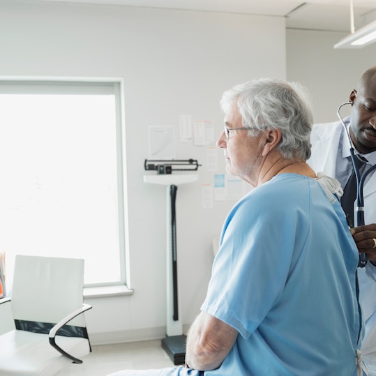 Doctor checking senior mans back in examination room