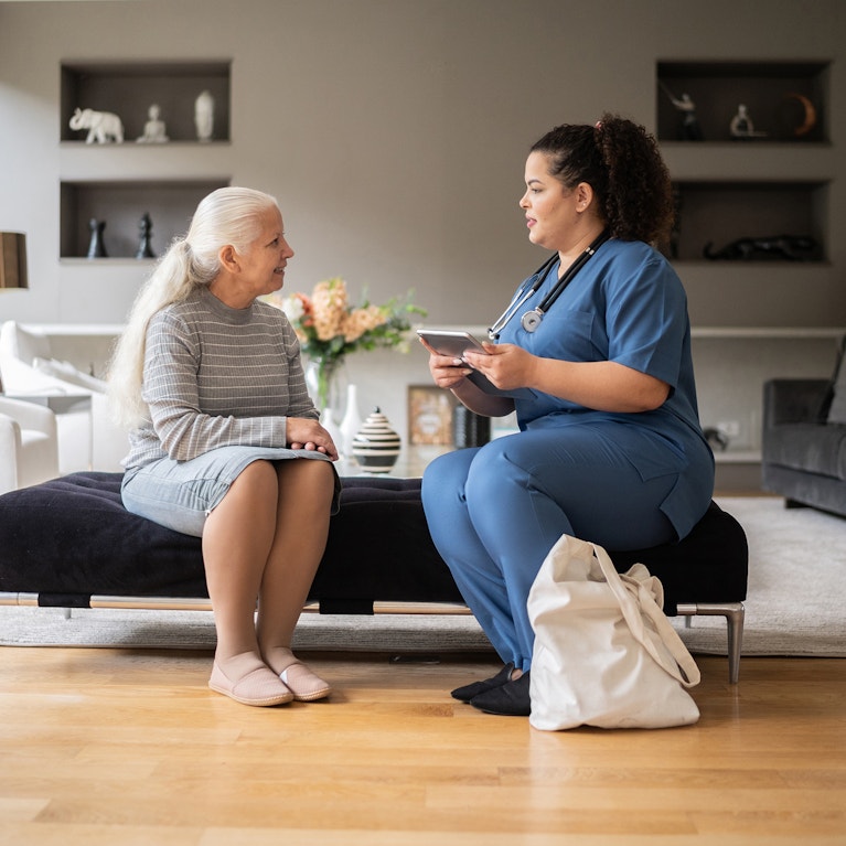 Senior woman talking to nurse during house call