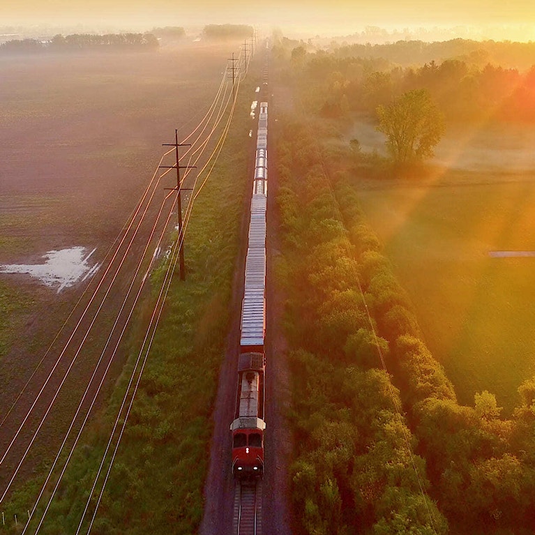 Train rolls through foggy rural landscape at sunrise, aerial view
