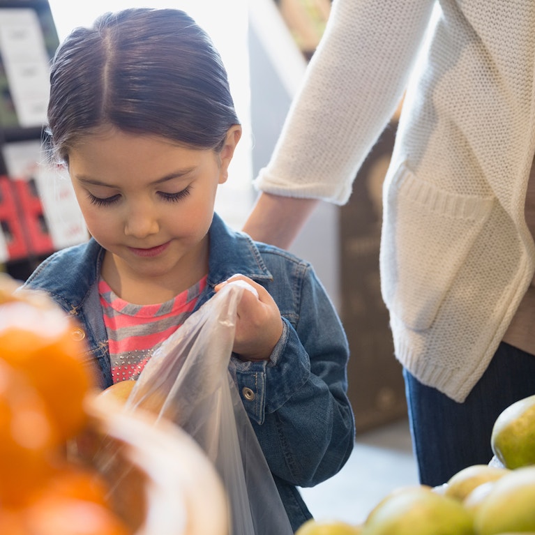 Girl bagging produce in market