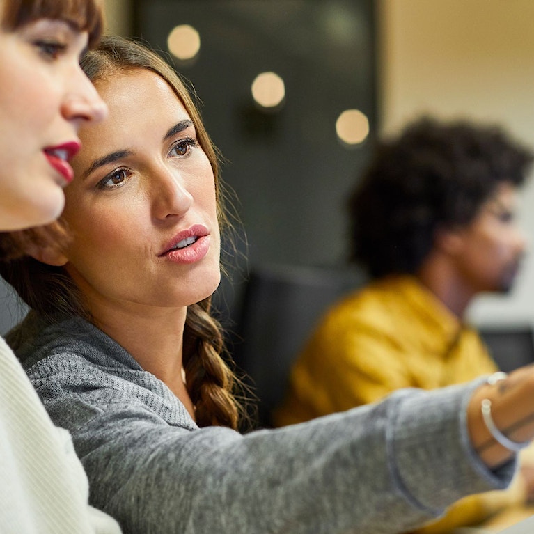 Coworkers discussing over computer in office