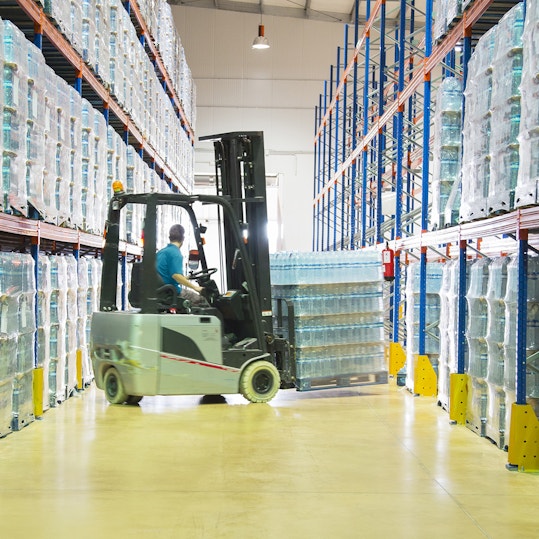 Man on forklift in storage warehouse.