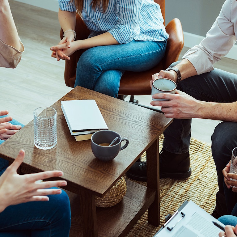 Group OF people having tea and water together around a coffee table