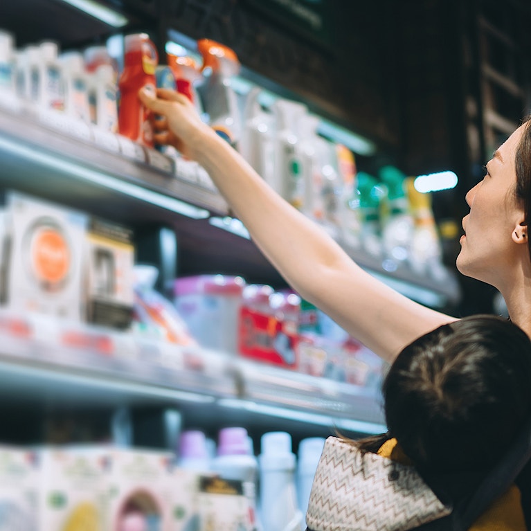 Young Asian mother grocery shopping with little daughter and choosing for baby necessities in a store