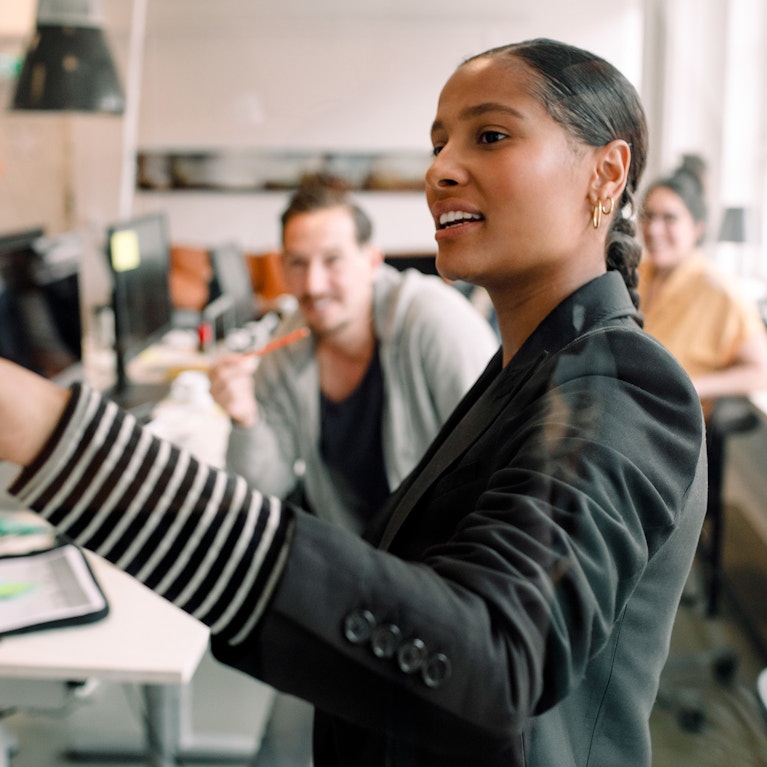 Young businesswoman addressing colleagues at office meeting