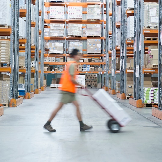 Worker pushing hand truck in warehouse