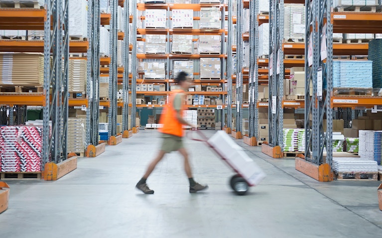 Worker pushing hand truck in warehouse