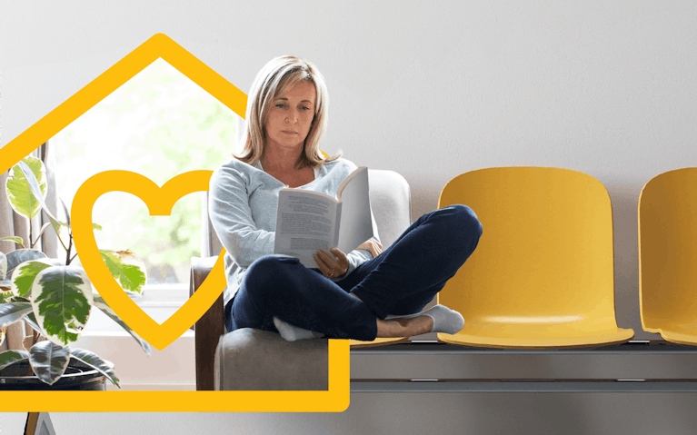 Woman seated on row of chairs reading document