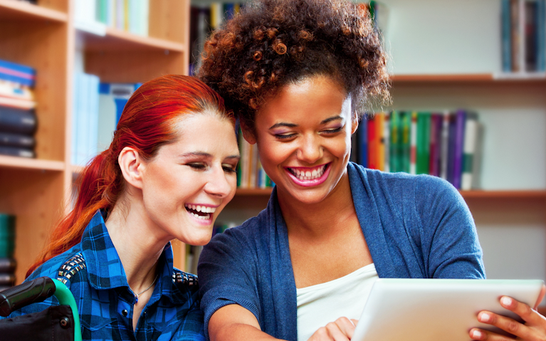 Two people smiling together whilst looking at soemthing